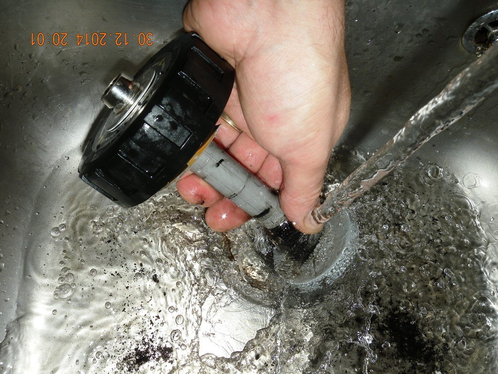 Real photograph of installed Adey MagnaClean filter trapping black magnetite iron oxide sludge